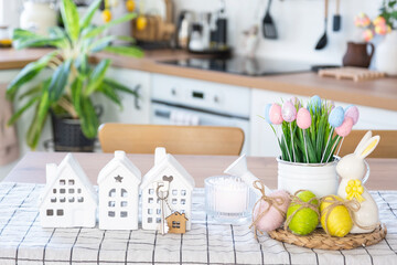 Key to house of cozy home with Easter decor with rabbit and eggs on table of kitchen. Building, design, project, moving to new house, mortgage, insurance, rent and purchase real estate