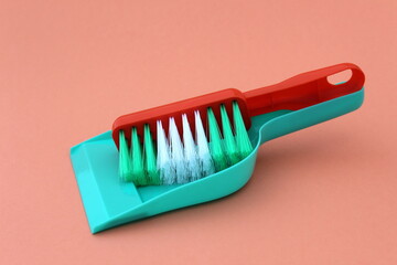 On a light background lies a brush and a scoop for cleaning green.	
