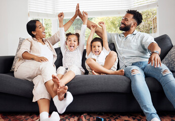 Happy parents and excited children celebrate on the sofa while watching tv. Fun family time,...