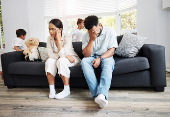Sad, unhappy and stressed parents sitting on a couch near their children at home after an argument. Frustrated, tired and annoyed mom and dad are angry at hyperactive, noisy and naughty kids - obrazy, fototapety, plakaty
