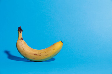 Ripe banana in the peel on a blue background close-up.