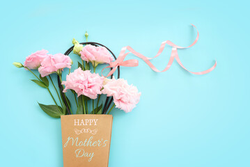 mother's day concept with pink flowers over pastel blue background