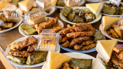 Many delicious fried banana snacks packed in plates placed amongst other Thai desserts.