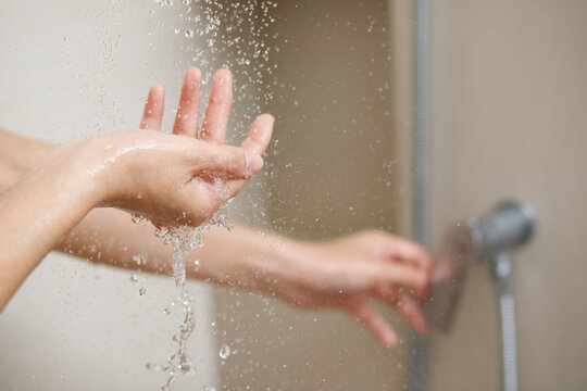 A woman uses hand to measure the water temperature from a water heater before taking a shower