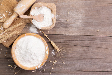 wheat flour in a wooden bowl There are ears of wheat on the table. Old wooden background - top view