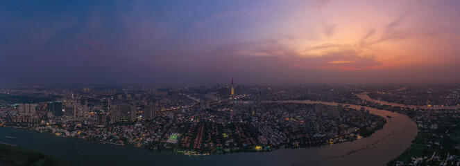 Aerial panorama  of Saigon river and Ho Chi Minh City skyline in Vietnam at dusk with landmark building at center.
