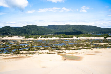 La gente se está bañando en un pequeño pozo natural en las dunas de Joaquina en la isla de Florianópolis en Brasil.

