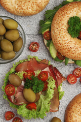 Fototapeta na wymiar Sesame bagels with tomatoes, ham and olives