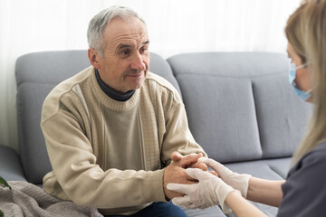 Nurse holding hand of senior man in rest home.