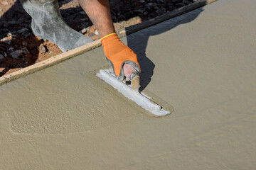 An employee plasters wet concrete cement floor using trowel after concrete has just been poured