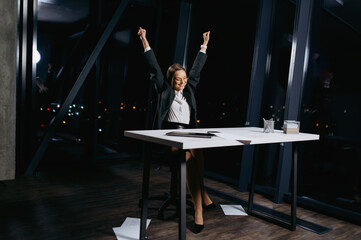 a young girl in classic clothes is happy at the desk. the end of the working day
