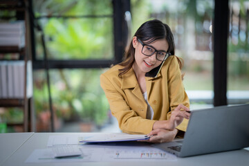 Happy businesswoman talking on mobile phone while analyzing weekly schedule in the office.