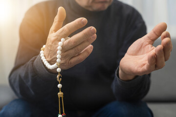 an elderly man prays with a rosary and the flag of the United Arab Emirates