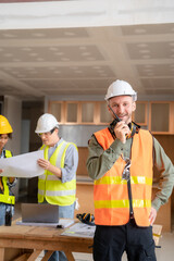 Architect colleagues mixed race working as a team discussing data working and tablet, laptop with on on architectural project at construction site at desk.