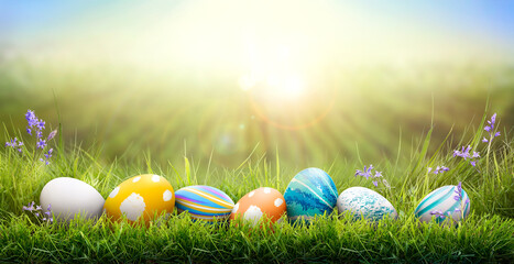 A collection of painted easter eggs celebrating a Happy Easter on a spring day with green grass meadow background with copy space.