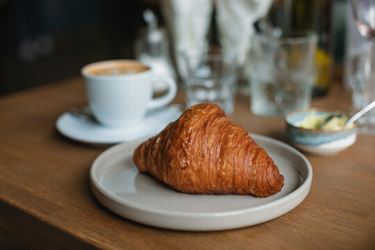 Close-up of a croissant, cup of coffee and water on a table
