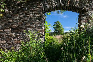 old stone wall with window in the meadow