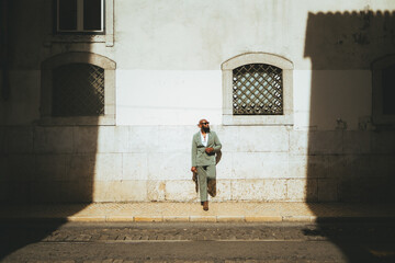 A black bald gentleman looks confident and poised as he stands in his green pastel suit against the...