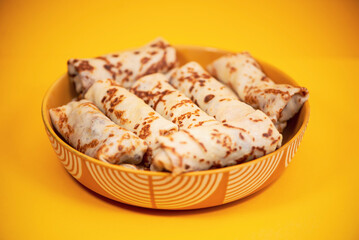 homemade pancakes with meat filling in a plate on a bright background