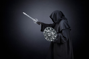 Fototapeta na wymiar Dark knight with sword and shield over dark misty background