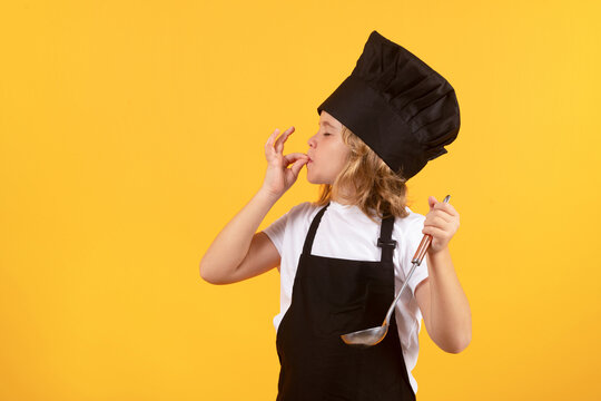 Funny kid chef cook with kitchen ladle, studio portrait. Cooking children. Chef kid boy in form of cook. Child boy with apron and chef hat preparing a healthy meal on studio isolated background