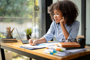 Black woman sitting in front of her considering work, office work Business woman sitting thinking work concept, Write a plan