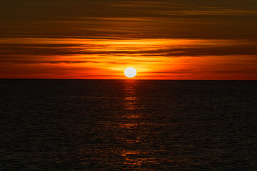 A sunset over the ocean with the sun setting behind it