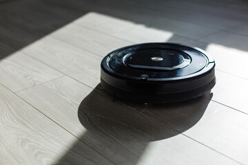 The robot vacuum cleaner drives on the laminate floor. Smart House. Home assistant concept.