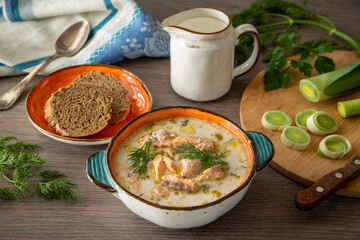 Finnish salmon soup with leek and cream on a wooden table background. Healthy food, traditional food.