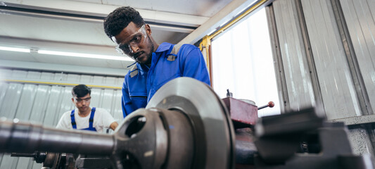 Diversity mechanic worker or metalworker using metal lathe machine operate polishing car disc brake...