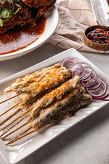 Portion of gourmet asian fried capelin skewers with onion