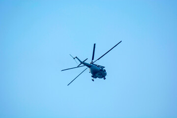 Fototapeta na wymiar Military helicopters is flying against isolated blue sky 