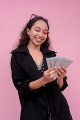 A young cheerful southeast asian woman counting a significant amount of cash on hand. Spending...