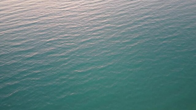 Beautiful sunset in Greece: camera pan from bottom to top. View from turquoise water to colorful sunset. Sunset  scenery in Kyllini, Greece and view to island of Kefalonia