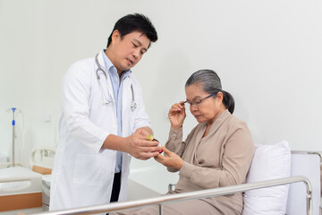Fototapeta premium Asian male doctor explaining medicine to elderly female patient in hospital.