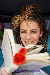 Catalonian independence day. Sant jordi day. Smiling woman with a rose reading a book looking at camera