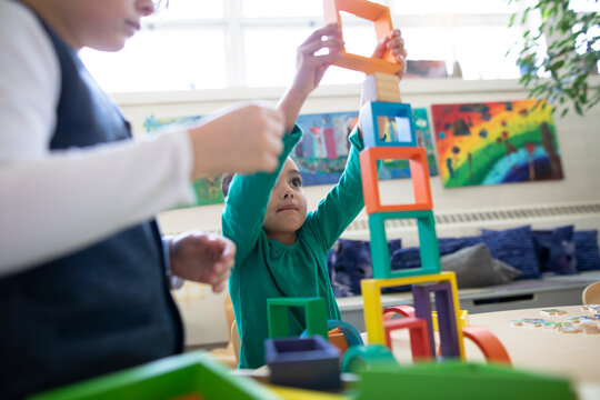 Preschool girl and boy playing with building blocks in classroom