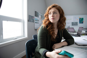Thoughtful businesswoman looking over shoulder in office