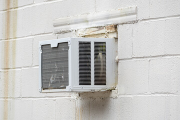 Battered Old Window Air Conditioning Unit In Cinder Block Wall