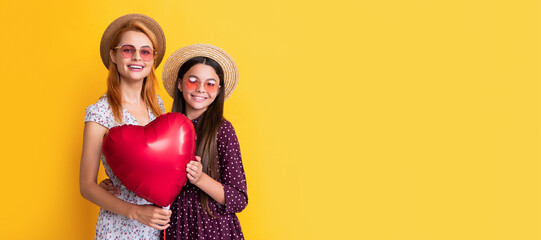Mother and daughter kid banner, copy space, isolated background. smiling mother and daughter holding love heart balloon on yellow background.