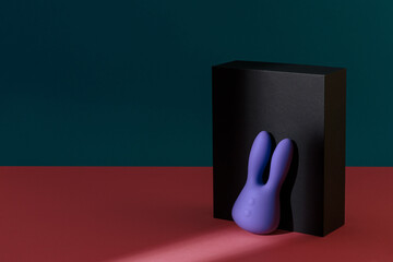 Violet dildo vibrator for clitoris with black gift box on colored background. Sex toy for adult