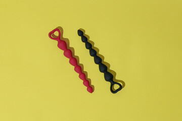 Anal plugs or dildo on yellow background with shadows. Sex shop concept. Sex toys for anal play
