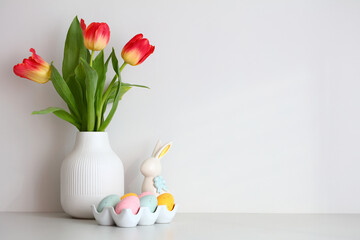 Vase of tulips, Easter bunny, Easter eggs on white wall background. Happy Easter concept.