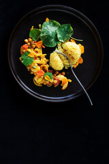 PRAWNS JASMINE RICE FORK NASTURTIUM LEAF GARNISH ON DARK BROWN RUSTIC PLATE ISOLATED ON BLACK BACKGROUND 