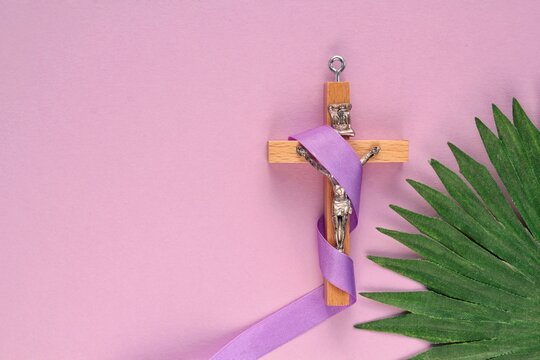 Christian religious wooden cross crucifix with violet ribbon on purple background. Catholic religion symbol. Good Friday, Lent Season, Palm Sunday, Ash Wednesday and Holy Week concept