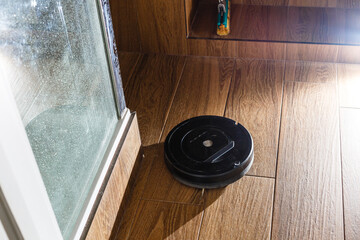 The robot vacuum cleaner drives on the laminate floor. Smart House. Home assistant concept.