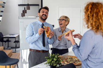 Coworkers eating pizza during break time in office
