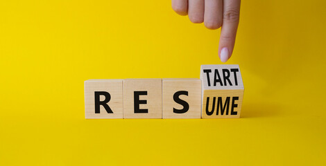 Restart and Resume symbol. Businessman hand points at turned wooden cubes with words Resume and...