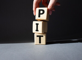 PIT - Personal Income Tax symbol. Wooden cubes with words PIT. Businessman hand. Beautiful grey background. Business and PIT concept. Copy space.