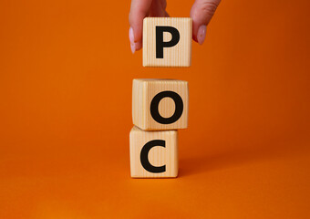 POC - Proof of Concept symbol. Wooden cubes with words POC. Businessman hand. Beautiful orange...